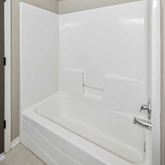 Thumbnail 14 of 22 A tub shower with chrome fixtures and a curved shower curtain rod.