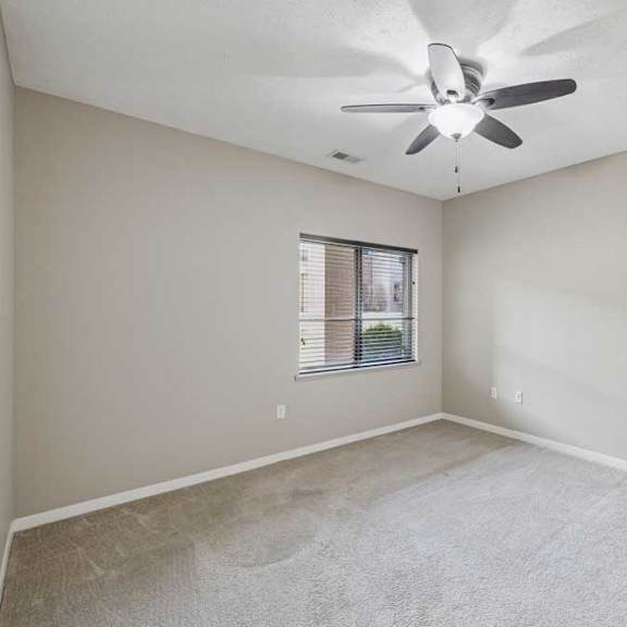 Thumbnail 12 of 22 A carpeted bedroom with a ceiling fan and a large window.