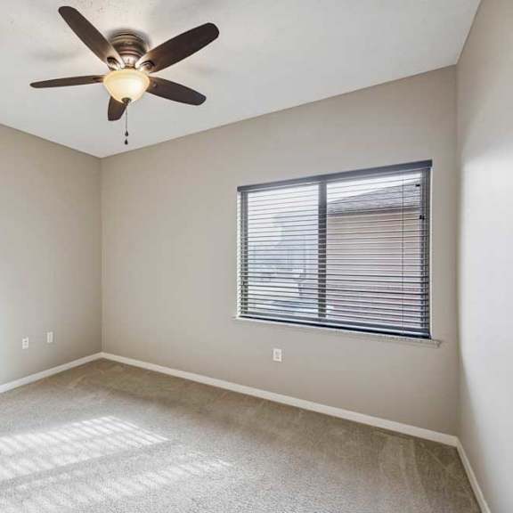 Thumbnail 17 of 22 A carpeted bedroom with a large window and a ceiling fan.