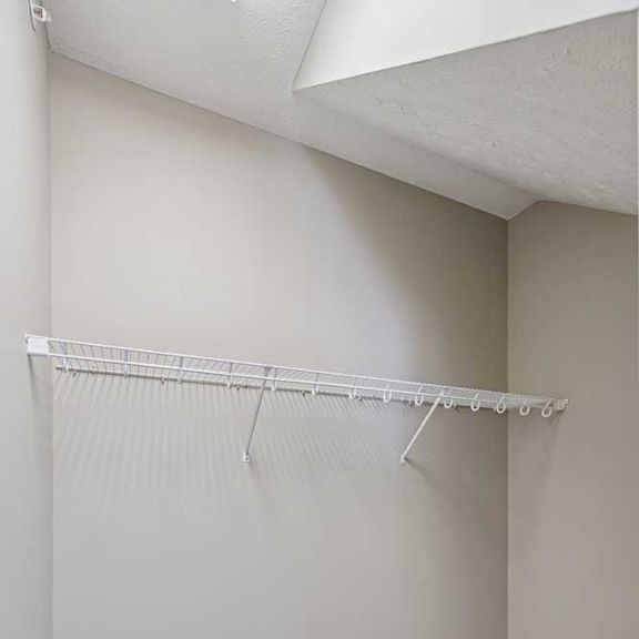 Thumbnail 16 of 22 A walk-in closet with a built-in wire shelf.
