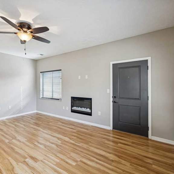 Thumbnail 4 of 22 A living room with hardwood-style flooring, a ceiling fan, and an electric fireplace.