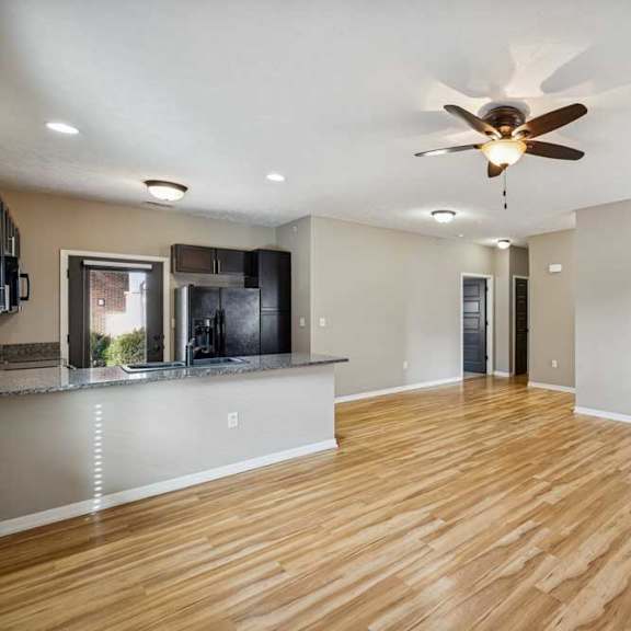 Thumbnail 3 of 22 A living room with hardwood-style flooring open to a kitchen with granite countertops.