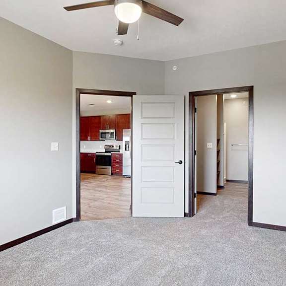 Thumbnail 18 of 51 A carpeted bedroom with a ceiling fan and a walk-in closet and attached bathroom.