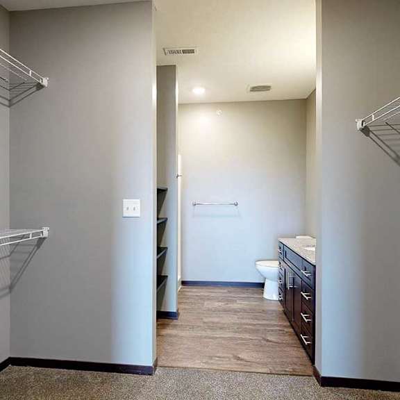 Thumbnail 21 of 51 A walk-in closet with shelves and an attached bathroom.