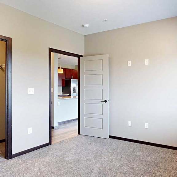 Thumbnail 26 of 51 A bedroom with a carpeted floor and a door open to the hallway.