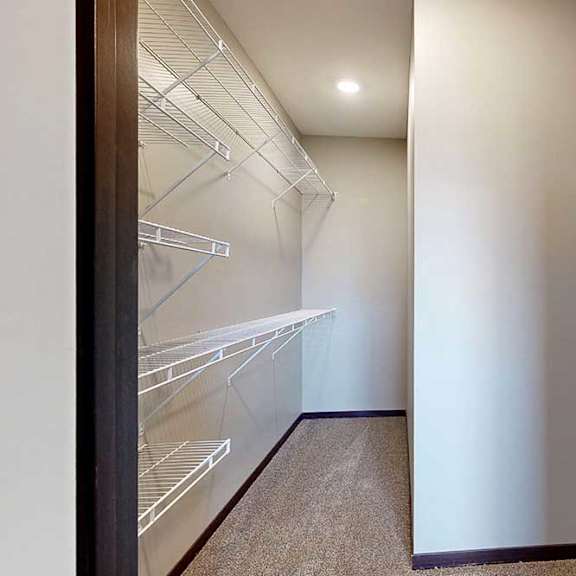 Thumbnail 29 of 51 A long walk-in closet with built-in shelves along the left, and additional hanging space on the right.