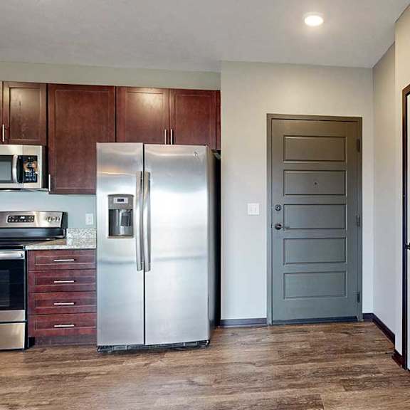 Thumbnail 4 of 51 A dark grey front door with a coat closet to the right, and a modern kitchen to the left.