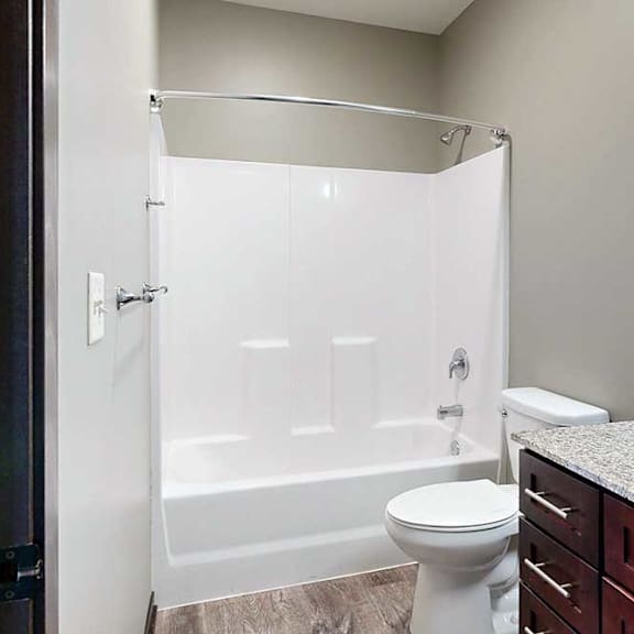 Thumbnail 31 of 51 A hallway bathroom with dark wooden cabinets, light granite counter, and a tub shower with chrome finishes.