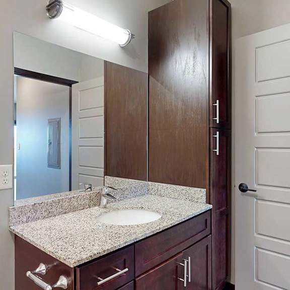 Thumbnail 30 of 51 A bathroom with a sink, mirror, and tall storage cabinet.