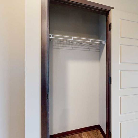 Thumbnail 5 of 51 A coat closet with a built-in wire shelf for storage and hanging space.