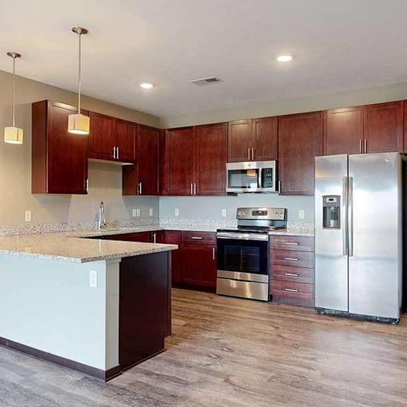 Thumbnail 7 of 51 A modern kitchen with dark cabinetry, stainless steel appliances, and granite counters.