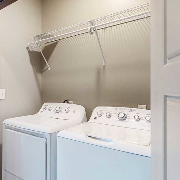 Thumbnail 32 of 51 A laundry area with a side-by-side washer and dryer, with overhead storage.