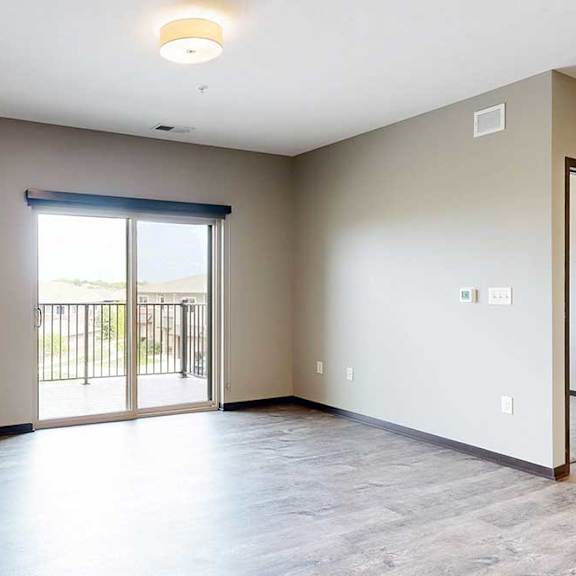 Thumbnail 13 of 51 A spacious living room with hardwood flooring and a sliding glass door to a balcony.