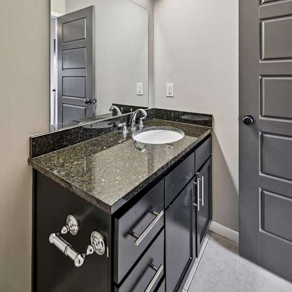 Thumbnail 10 of 25 A bathroom with a sink, mirror, and black cabinets.