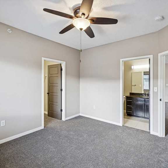 Thumbnail 24 of 25 A room with a ceiling fan and a grey carpet.