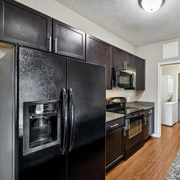 Thumbnail 5 of 25 A kitchen with black appliances and wooden cabinets.