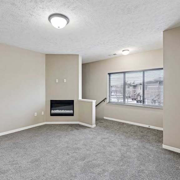 Thumbnail 21 of 25 A living room with a fireplace and a window with blinds.