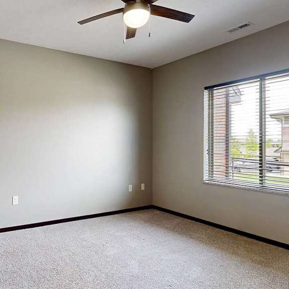 Thumbnail 23 of 33 A carpeted bedroom with a large window and a ceiling fan.