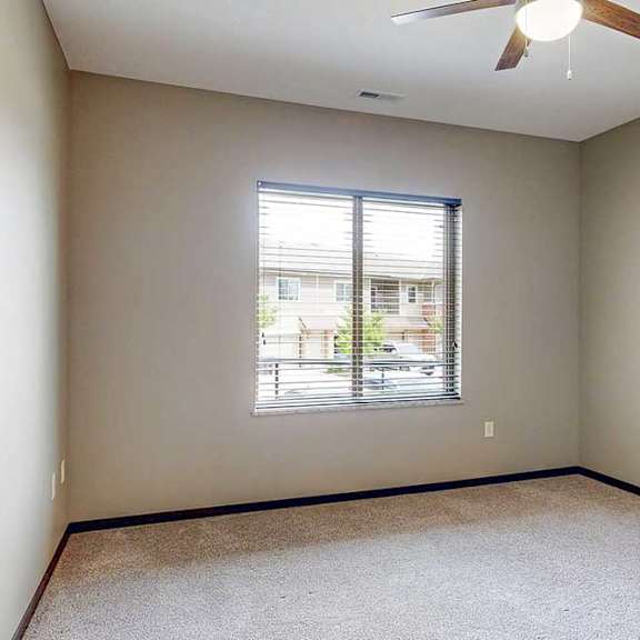 Thumbnail 22 of 33 A carpeted bedroom with a large window and a ceiling fan.