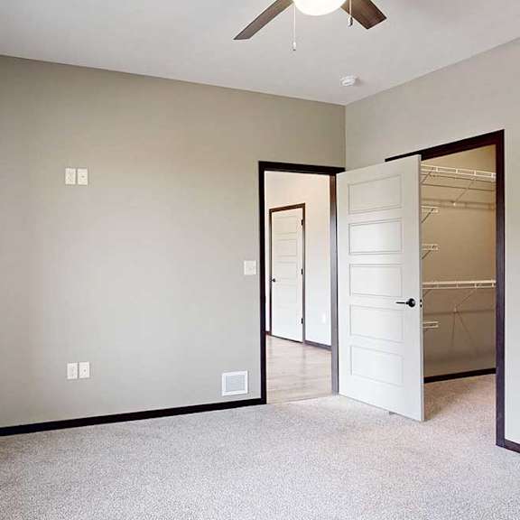 Thumbnail 21 of 33 A carpeted bedroom with a large window, a ceiling fan, and a walk-in closet.