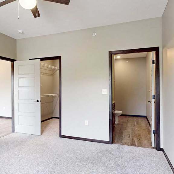Thumbnail 24 of 33 A carpeted bedroom with a ceiling fan, a walk-in closet, and an attached bathroom.