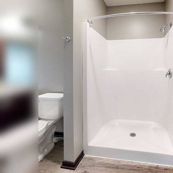 Thumbnail 28 of 33 A bathroom with a walk-in shower with chrome finishes and a curved curtain rod.