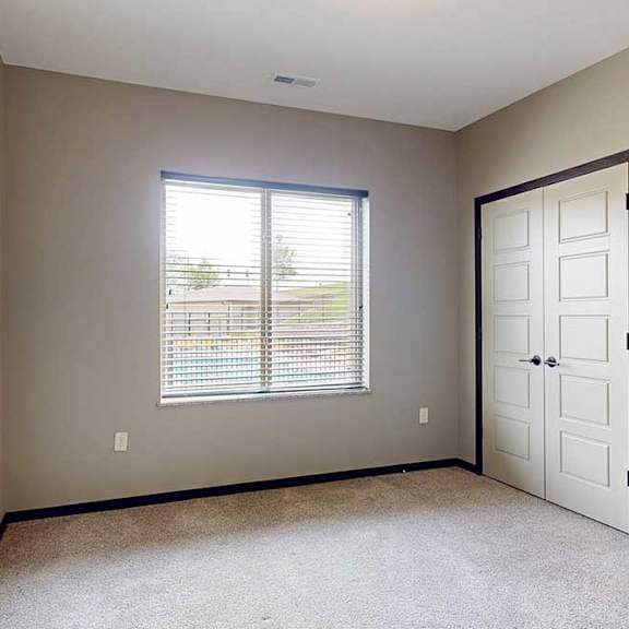 Thumbnail 29 of 33 A bedroom with two closed side-by-side closets, and a large window.