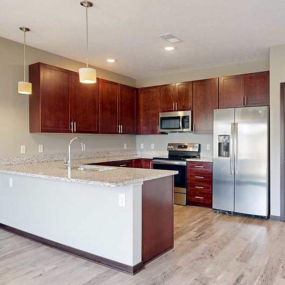 Thumbnail 11 of 33 A modern kitchen with wooden cabinets, granite counters, stainless steel appliances, and a pantry to the side.