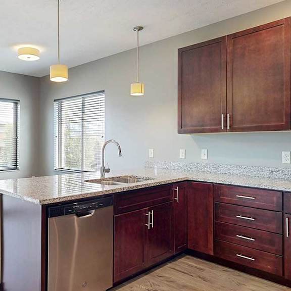 Thumbnail 7 of 33 A kitchen peninsula with a sink and dishwasher in front of a dining area.