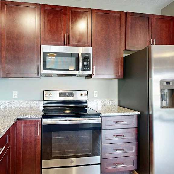 Thumbnail 15 of 33 A modern kitchen with wooden cabinets, granite counters, and stainless steel appliances.