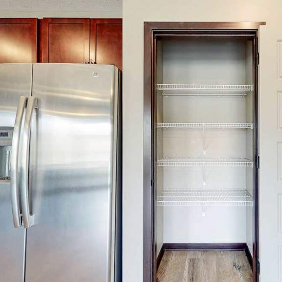 Thumbnail 13 of 33 A pantry with built-in shelving next to a stainless steel fridge.