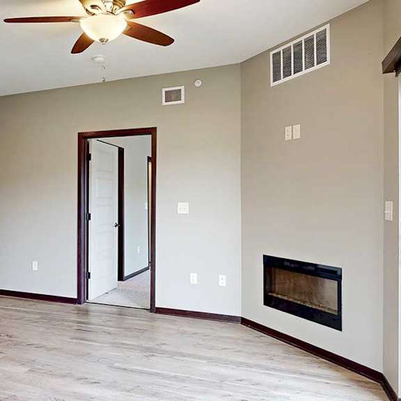 Thumbnail 20 of 33 A living room with a ceiling fan, an electric fireplace, and wood-style flooring.