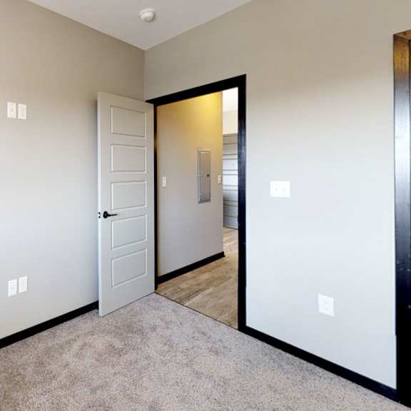 Thumbnail 8 of 10 A room with a carpeted floor and a white door.