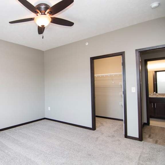 Thumbnail 11 of 14 A room with a ceiling fan and carpeted floor.