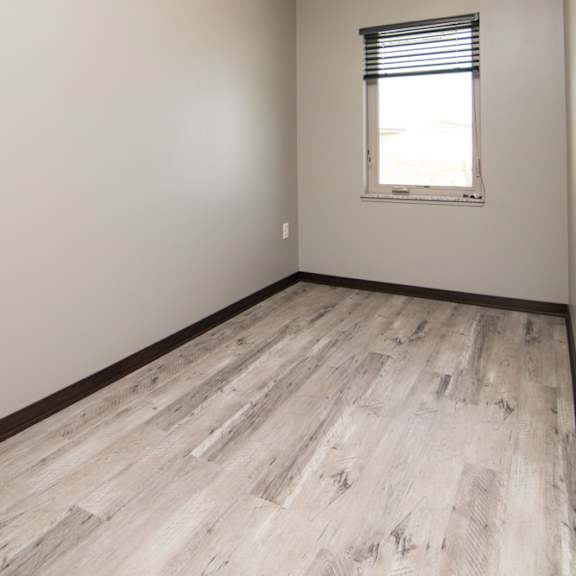 Thumbnail 9 of 14 A room with a window and wooden flooring.