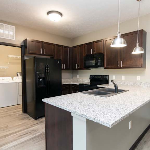 Thumbnail 4 of 14 A kitchen with black appliances and brown cabinets.