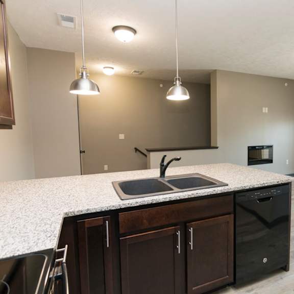 Thumbnail 7 of 14 A kitchen with a granite countertop and dark brown cabinets.