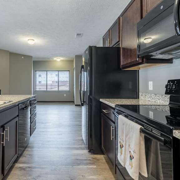 Thumbnail 7 of 12 A kitchen with black appliances and a marble countertop.