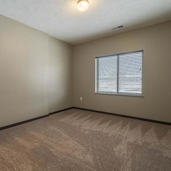 Thumbnail 8 of 12 A room with a carpeted floor and a window with blinds.