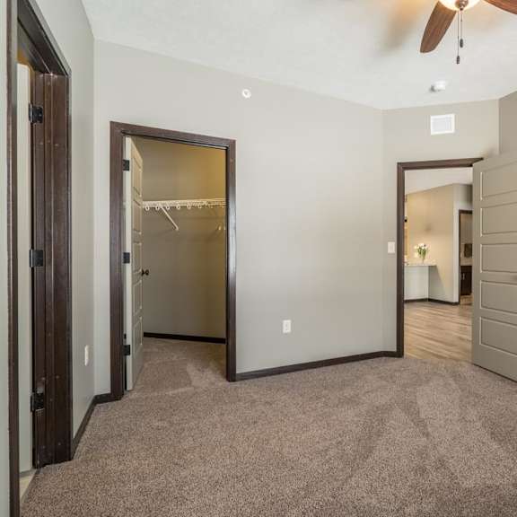 Thumbnail 11 of 12 A room with a ceiling fan and a carpeted floor.