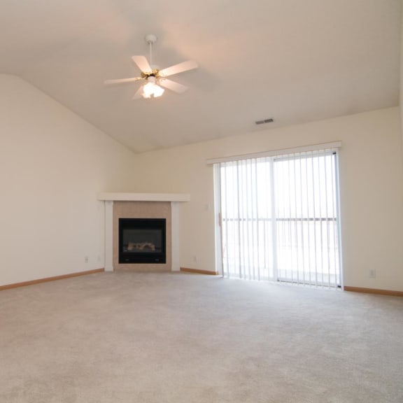 Thumbnail 9 of 15 an empty living room with a ceiling fan and a fireplace