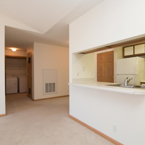 Thumbnail 6 of 15 an empty living room and kitchen with a sink and refrigerator