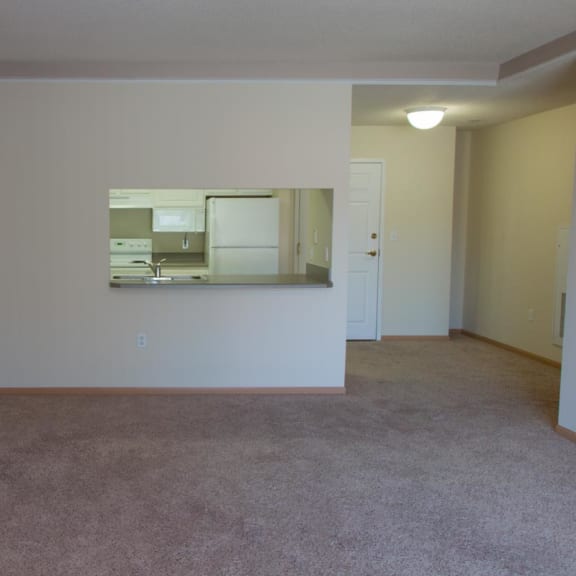 Thumbnail 7 of 13 an empty living room with a kitchen in it