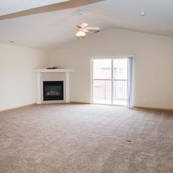 Thumbnail 7 of 21 an empty living room with a fireplace and a ceiling fan