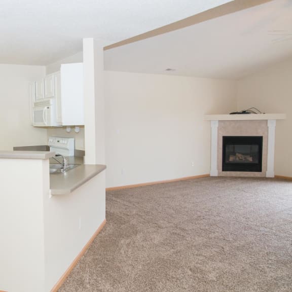 Thumbnail 2 of 21 an empty living room with a kitchen and a fireplace