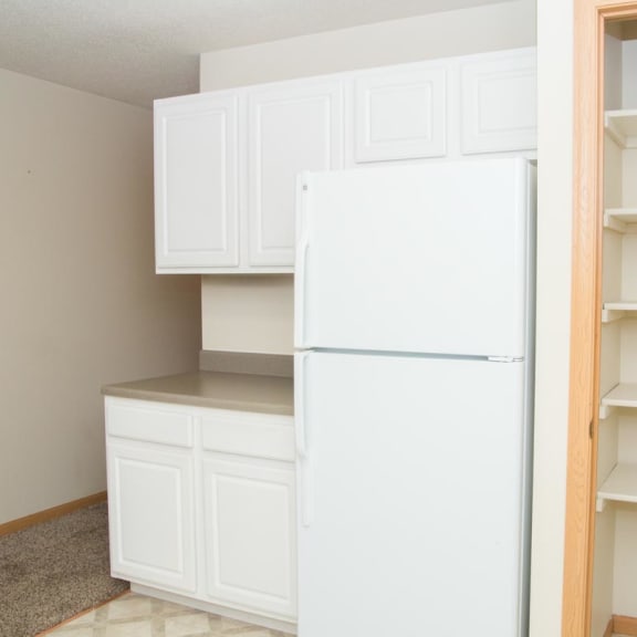 Thumbnail 6 of 21 a white kitchen with a white refrigerator and shelves