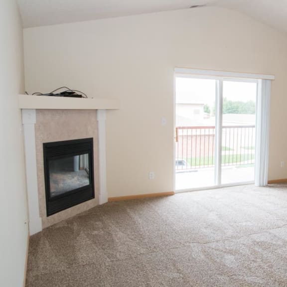 Thumbnail 8 of 21 a living room with a fireplace and a door to a balcony