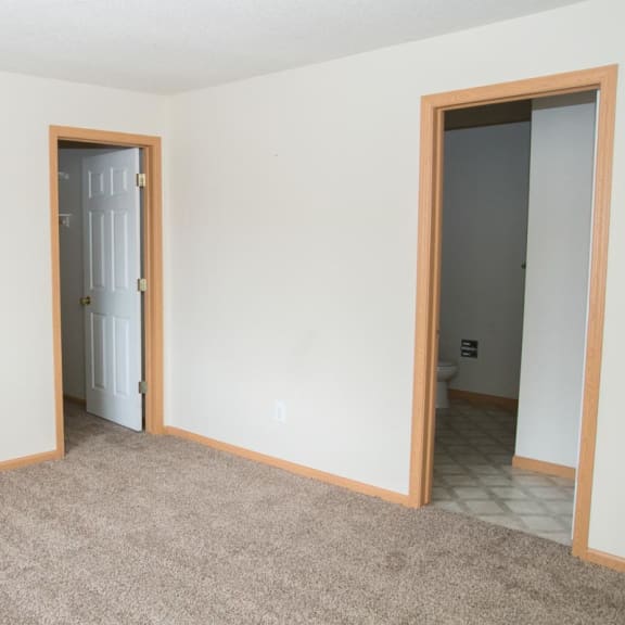 Thumbnail 14 of 21 an empty living room with two doors and a carpet