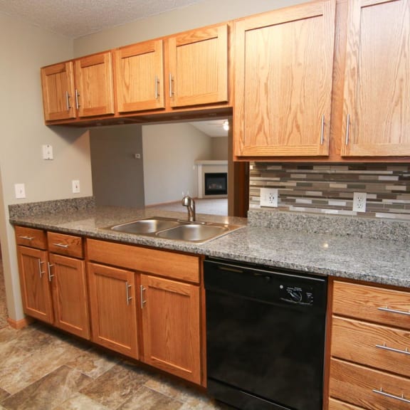 Thumbnail 7 of 27 a kitchen with wooden cabinets and granite counter top and a black dishwasher