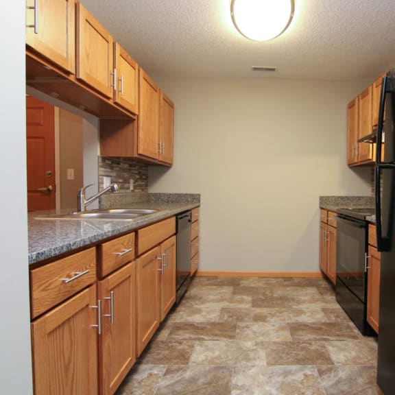 Thumbnail 3 of 27 a kitchen with wooden cabinets and a black refrigerator